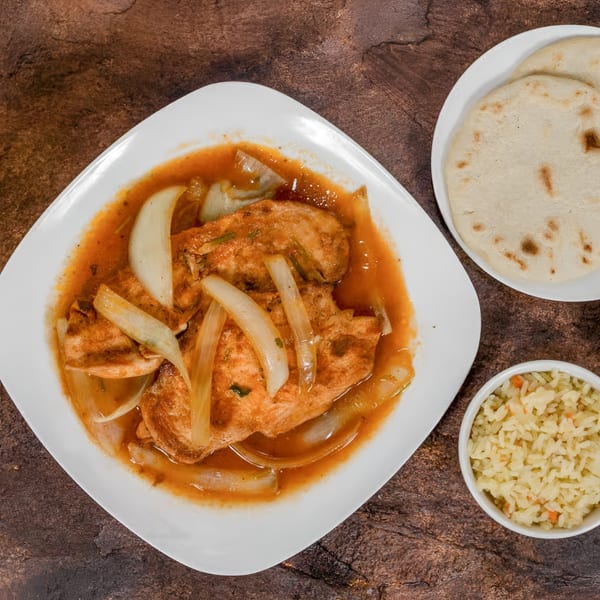 Mi Casita's Mexican chicken dish with onions in sauce, served with rice and tortillas.