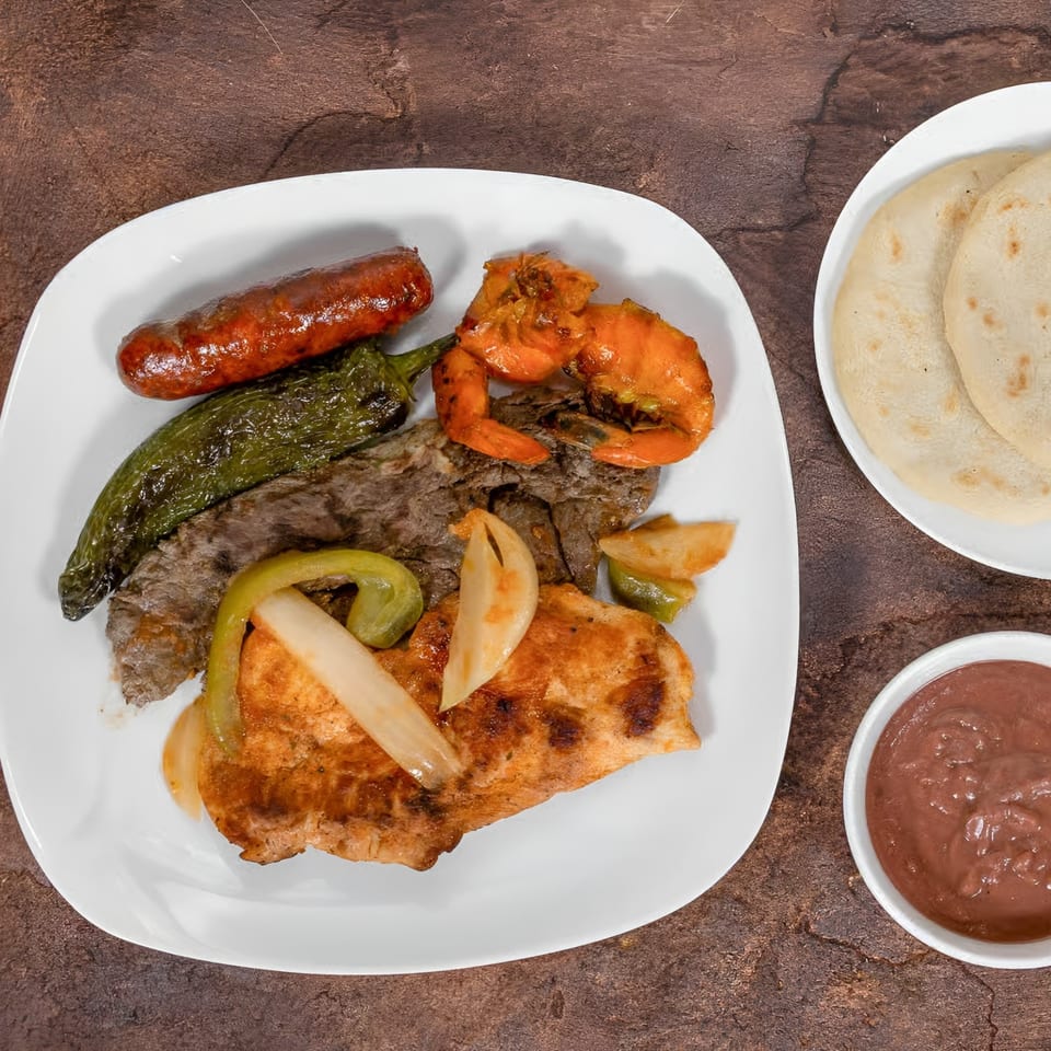 Mi Casita Restaurant's mixed grill with sausage, shrimp, steak, chicken, peppers, onions, tortillas, and sauce.