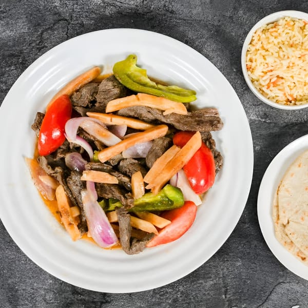 Mi Casita Restaurant's Lomo Saltado with steak, bell peppers, onions, fries, rice, and tortillas.