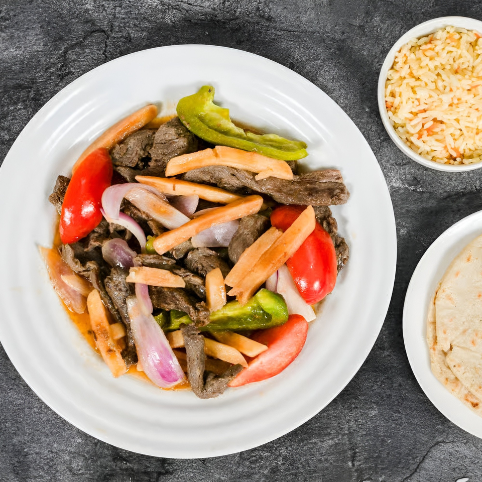 Mi Casita Restaurant's Lomo Saltado with steak, bell peppers, onions, fries, rice, and tortillas.