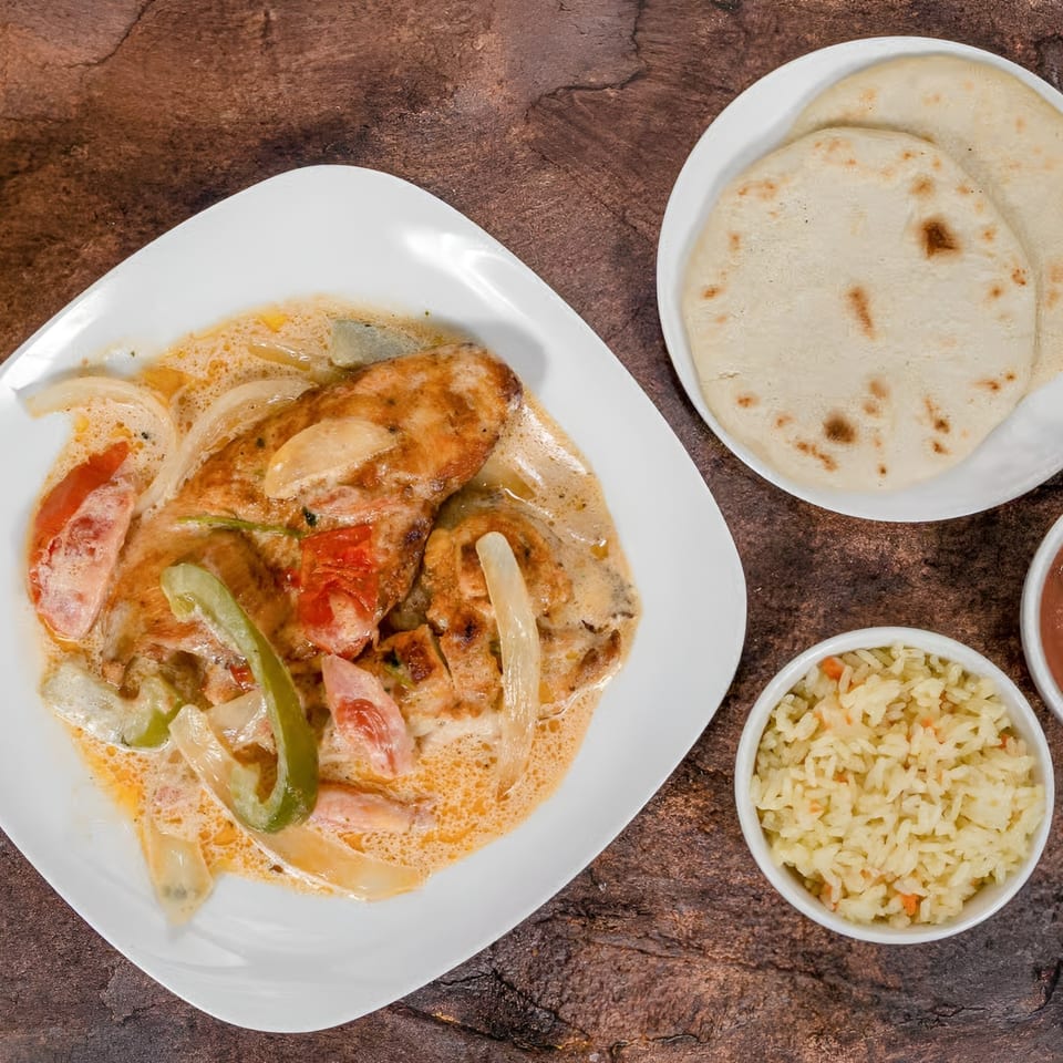 Mi Casita's chicken in creamy sauce with peppers and onions, served with rice and tortillas.