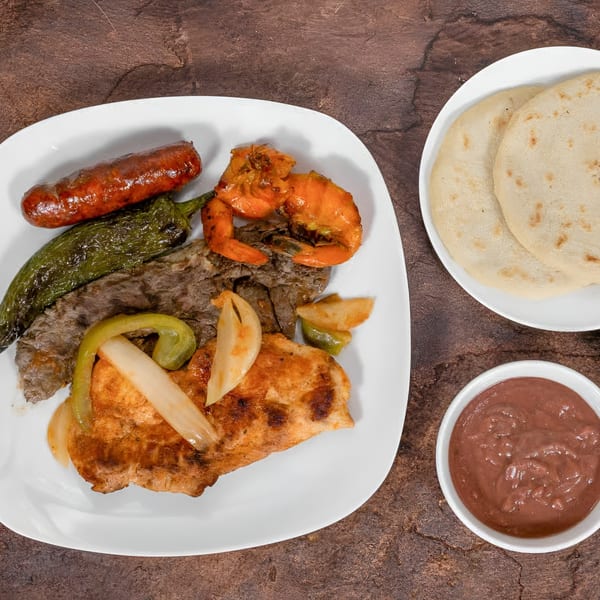 Mi Casita's mixed grill with sausage, shrimp, steak, chicken, peppers, onions, tortillas, and beans.