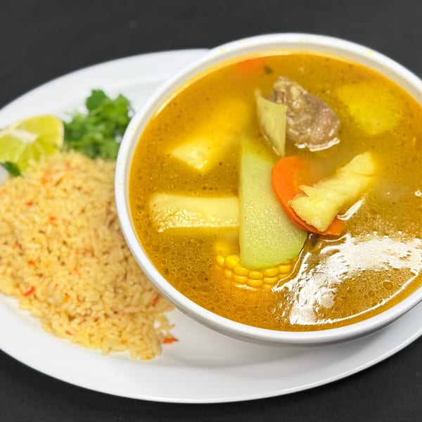 Hearty Mi Casita Mexican soup with beef, corn, chayote, carrots, and potatoes, served with rice and lime.