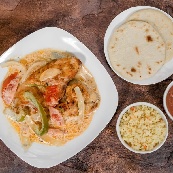Mi Casita's chicken dish with creamy sauce, bell peppers, onions, rice, salsa, and tortillas.